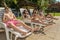 Four friends sunbathe on the sun loungers on the beach