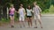 Four funny young people dancing while holding hands, enjoying time outdoors