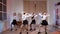 Four girls in black skirts and white shirts are dancing indoors