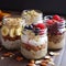 four glass jars of overnight oats with fruit, nuts and berries