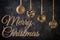 Four golden Christmas balls hanging on ribbons. Next to the inscription Merry Christmas on a black textured background.