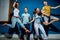 Four good-looking friends are laughing while jumping in front of the blue wall having confident and happy looks