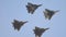 Four green camouflage coloring military fighter jets flying in the sky