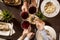 Four hands with red wine toasting over served table with food