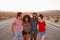 Four happy friends standing on a desert highway, close up