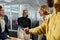 Four happy young multiracial adults in businesswear shaking hands in conference room in office