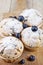 Four homemade fresh muffins with sugar powder and blueberries on cutting board on rustic wooden table