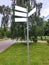Four information signs pointers on a metal pole on a green lawn in a summer park