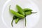 Four jalapeÃ±o chilis with stem on a white background