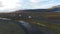 Four jeeps ride on a gravel road amid mountains and a glacier. Travel through the mountains and glaciers of Iceland