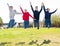 Four joyful teens jump on a lawn