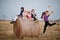 Four kids with mother having fun on haycock at field