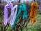 Four knitted multy-colored scarfs hang on a bush.