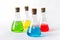 Four laboratory flasks with cork plugs and colorful liquids