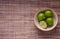 Four limes in a cup on mat background