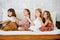 Four little girls about the same age sitting on a sofa one behind another