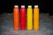 Four long bottles with paints, autumn colors, red, yellow, orange, stand on dirty floor during repair