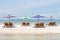 Four lounge chairs and umbrella at the white sand beach