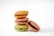 Four macaroons on white cutout. Green, pink and orange french sweets with cream.