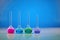 Four medical flasks with colorful chemical reagents for tests, blue background. Laboratory research of Coronavirus