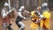 Four men knightes having a training fight on the field in the middle of the forest