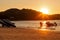 Four mens at sunset pull hydrocycle out of the water. Workers of the beach. Water bike loaded onto a rickshaw trailer