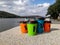 Four multi-colored disposable portable paper coffee cups of different sizes on background of river. Take-Out Coffee.