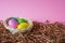 Four multicolor Easter eggs in a basket on pink background. Easter celebratory wallpaper with copy space