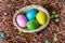 Four multicolor Easter eggs in a basket on wooden background. Easter celebratory wallpaper with copy space