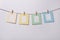 Four multicolored paper photo frames hanging on the rope on white background