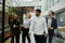 Four multiracial young adults in businesswear walking and laughing in corridor of office