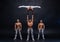 Four muscular man perform difficult acrobatic tricks on black studio