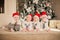 Four newborn kids in red Santa`s caps sitting on the floor in white Christmas studio
