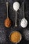 Four old spoons with brown, white, icing sugar and cocoa powder