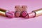 Four old used lipstick tubes lie on a pink background