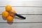 Four oranges on a white table top wiht a knife