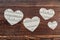 Four paper hearts on wooden background.