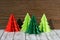 Four paper origami Christmas trees on a wooden background