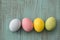 Four pastel colored Easter eggs on blue wood background