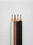 Four pencils, white brown dark brown and black, on white corrugated plastic board