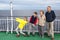 Four people family taking selfie with stick, having sea trip on a cruise ferry boat, grandparents with grandchildren