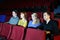 Four people watch movie in movie theater.