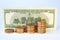 Four piles yellow metal dollars in front of old 100 US dollar banknote. On a white background.