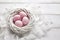 Four pink Easter eggs in the white nest and feathers