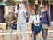 Four positive teens in protective masks walk along spring street