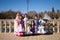 four pretty little girls dancing flamenco dressed in typical gypsy costume pose in a famous square in seville, spain. In the