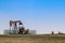 Four pumpjacks extracting oil or gas out on the horizon of a winter field under blue sky