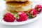 Four raspberries on plate, pancakes background