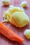 Four raw potatoes and one peeled carrot on a wooden background