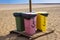 Four recycle bins for different waste. Paper, glass, food, plastic. Beach, sand